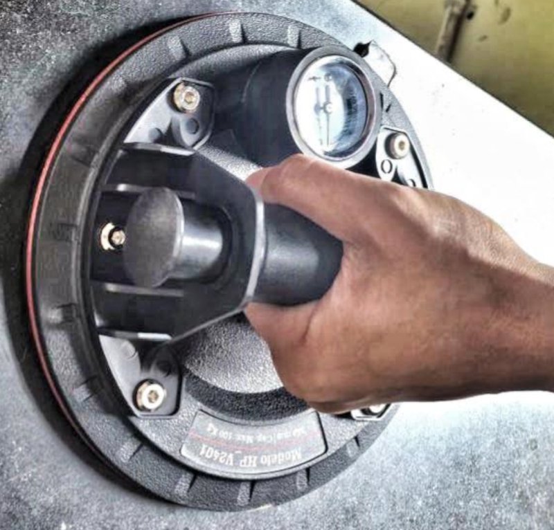 Técnico instalando una mampara de ducha de cristal con ventosa de succión en Madrid. Herramienta profesional con manómetro y agarre ergonómico.